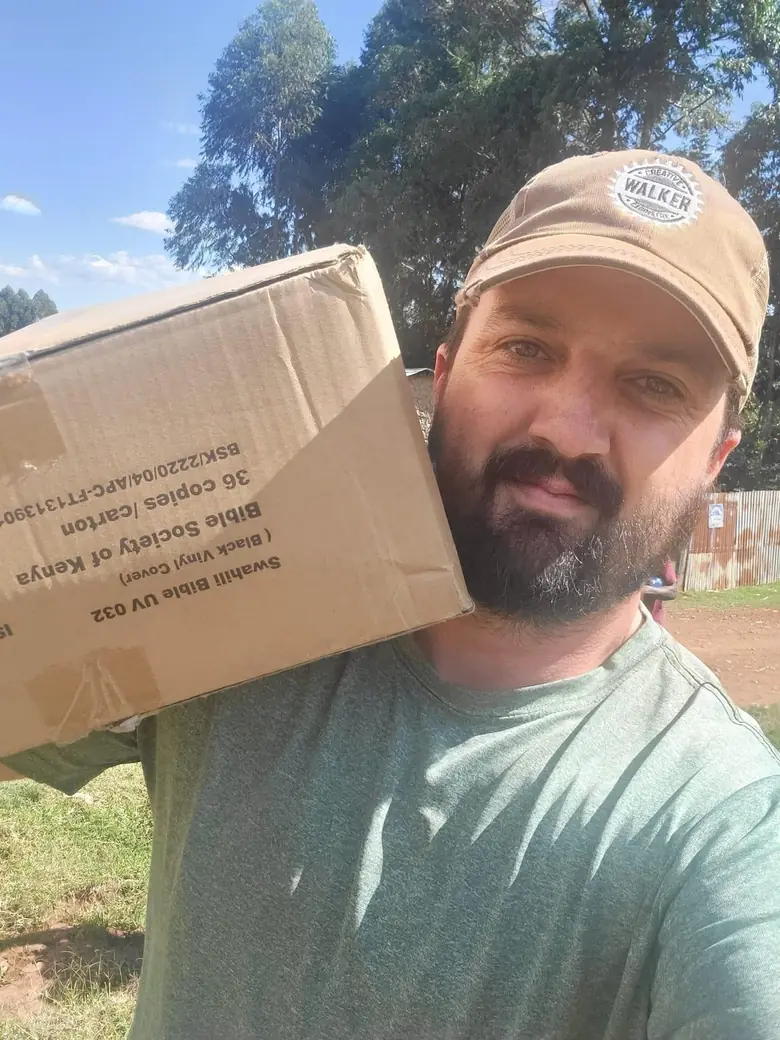 A Bible Runner carrying a box of Bibles in the field